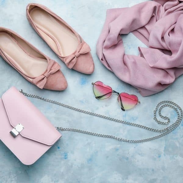 A styled flatlay with pink ballet slippers, pink purse and pink scarf