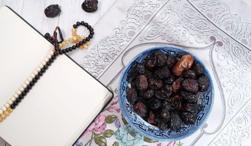 Notebook with dates sitting on a prayer mat with prayer beads