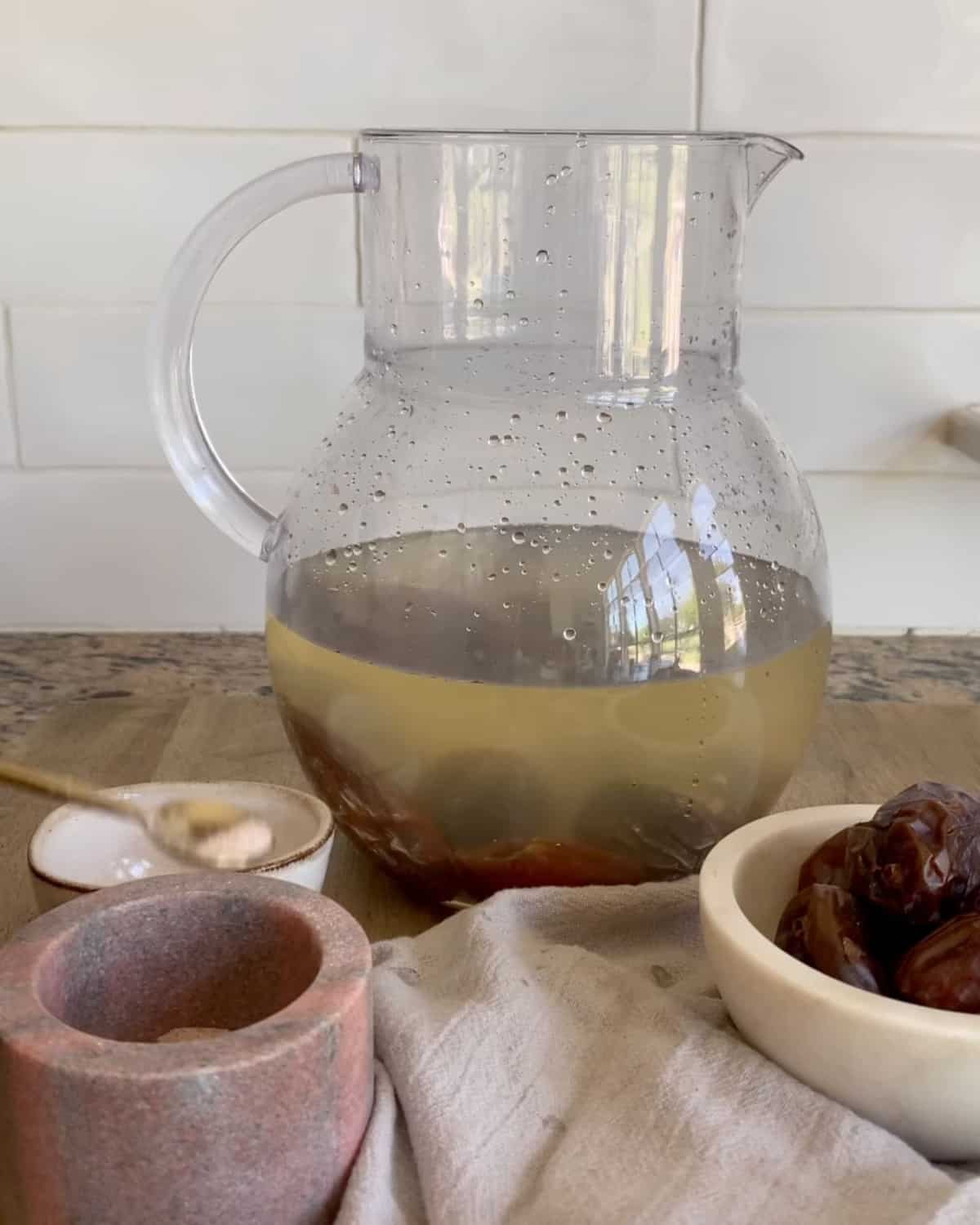 Nabeez- A prophetic drink made with dates or raisins in a jug with a bowl of dates and some pink salt beside it.